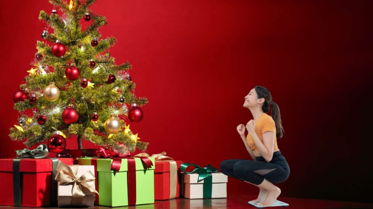 Donna sulla bilancia vicino all'albero di Natale